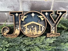 a wooden sign that says joy with nativity scene in the center and stars above it