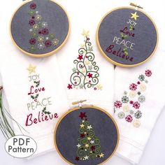 four embroidered christmas trees on white linens with the words joy, peace, and believe