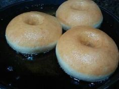 three doughnuts sitting on top of a black pan