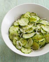 a white bowl filled with sliced cucumbers on top of a wooden table