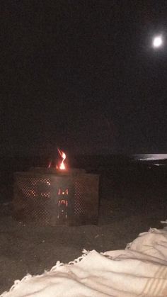 there is a fire pit on the beach at night with no one around it,