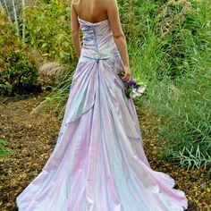 a woman in a purple and blue dress is walking through the grass with her back to the camera