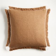 a brown pillow with fringes on the front and back, against a white background