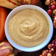 a bowl of hummus surrounded by fall fruits and vegetables