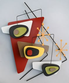 three pieces of art hanging on the wall with different shapes and sizes, including an abstract design