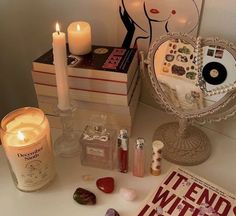 a table topped with books and candles next to a mirror