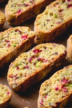 there are many pieces of bread on the baking sheet with cranberries and other toppings