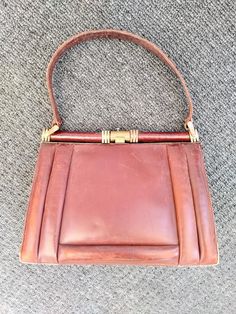 Original vintage antique 1940's Brown Leather Brass clasp handbag All stitching intact apart from pocket corner inside - brass framework is in need of some repair (see picture) but works fine as it is Some age related wear and tear and in need of a new clasp opener - however lovely vintage bag and plenty of wear left in it - Possibly made in France - please ask if you require more photos Classic Vintage Brown Bag With Brass Hardware, Vintage Brown Bag With Top Carry Handle, Vintage Brown Leather Top Handle Bag, Retro Vintage Brown Top Handle Bag, Vintage Brown Bag With Gold-tone Hardware, Vintage Bags, Brown Leather, Vintage Antiques, Purses And Handbags