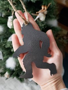 a person holding up a metal ornament with a bear on it's back