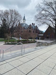 a large building with a clock tower next to a walkway and trees in front of it