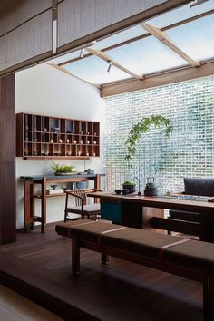 a room that has some chairs and a table in it with plants on the shelves