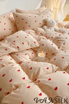 a teddy bear sitting on top of a bed covered in sheets and pillows with hearts