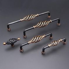 four black and gold metal handles on a gray surface