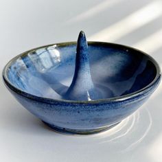 a blue bowl with a spoon sticking out of it's side on a white surface