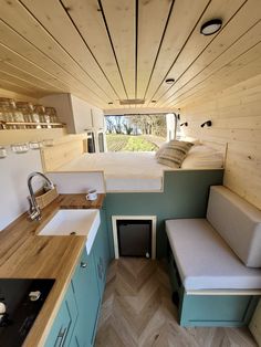 the interior of a tiny home with wood paneling and blue cabinets, counter tops, and sink