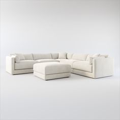 a large white sectional couch sitting on top of a white floor next to a footstool