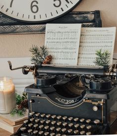 an old fashioned typewriter with sheet music on it next to a candle and clock