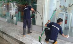 two men in blue shirts are cleaning windows