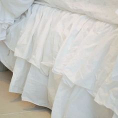 a white bed with ruffled bedspread and pillows