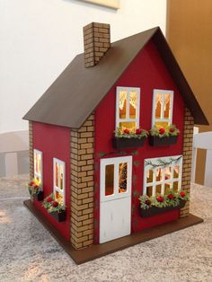 a red doll house with windows and plants