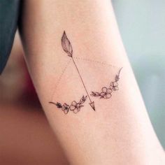 a woman's arm with an arrow and flowers on it