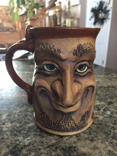 a close up of a coffee cup on a counter with a face painted on it