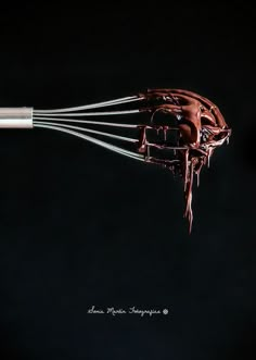 a whisk is being used to make chocolate frosting on a black background