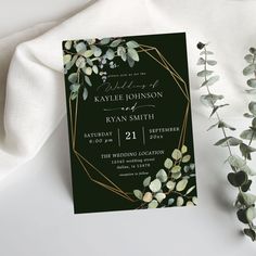 an elegant wedding card with greenery and gold foil on the front, is displayed next to some flowers