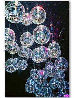 several disco balls hanging from the ceiling in front of a black background with lights on them