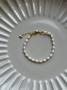 Minimalistic 18k gold plated freshwater pearl bracelet with 18k gold plated beads. It forms a gorgeous base in your jewellery collection and goes nicely with any outfits. Adjustable. Please note pearls are organic and shape and colour may vary. DETAILS: - Material:  Freshwater pears 3,4mm/18k gold plated beads and a closure - Bracelet length: 18cm with an extension chain 21cm overall - Hypoallergenic  -Nickel free - Recycled - Tarnish resistant MATERIAL AND CARE: - Our beautiful pieces are made out of high quality 18k gold plated stainless steel  material which holds up to the elements of daily life.   - To extend the life of the jewellery we highly advise to: ~ wipe clean with a polishing cloth after wearing to keep it clean and shiny ~ store in a cool dry place ideally in our soft pouch. Minimalist Beaded Jewelry, Minimalistic Bracelet, Small Bead Bracelet, Gold Beaded Bracelet, Handmade Jewlery, Bracelet Dainty, Dainty Bracelet, Gold Bead Bracelets, Freshwater Pearl Bracelet