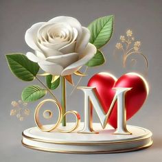 a white rose sitting on top of a table next to a red heart and letter m