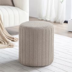 a round ottoman sitting on top of a white rug