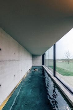 an indoor swimming pool in the middle of a room with large windows on both sides