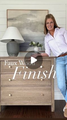 a woman standing next to a wooden dresser