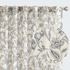 a curtain with a floral design on it and a round plate hanging from the side