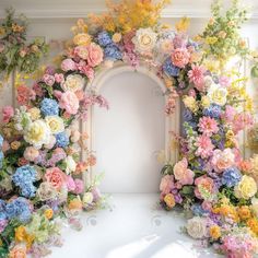 an arch covered in flowers and greenery next to a white door