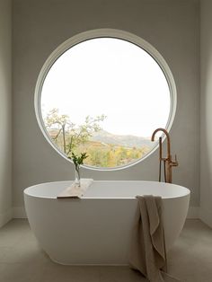 a large round window in the middle of a bathroom with a white bathtub next to it