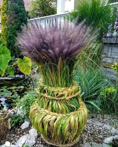 a planter made out of grass and other plants in a garden with rocks on the ground