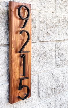 a wooden sign with the number twenty five on it's side next to a brick wall