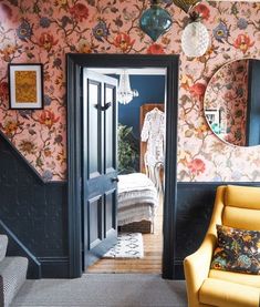 a living room filled with furniture and walls covered in floral wallpaper, along with a yellow chair