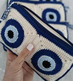 a hand holding up a blue and white purse with an evil eye design on it