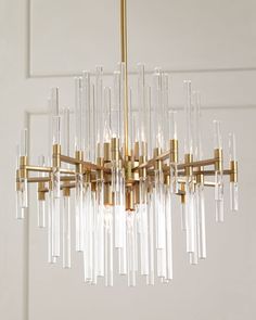 a chandelier hanging from the ceiling with clear glass tubes and gold fixtures on it