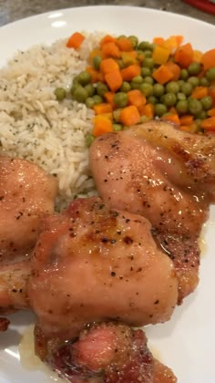 a white plate topped with chicken, rice and veggies next to carrots