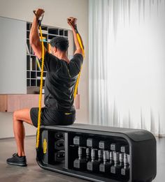 a man sitting on top of a black box while holding a pair of yellow straps