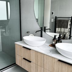 two white bowls sit on top of a counter in front of a mirror and shower