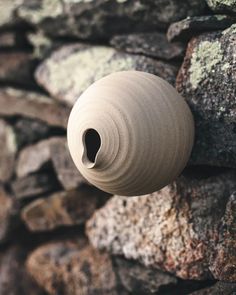 a stone wall with a vase hanging on it's side next to some rocks