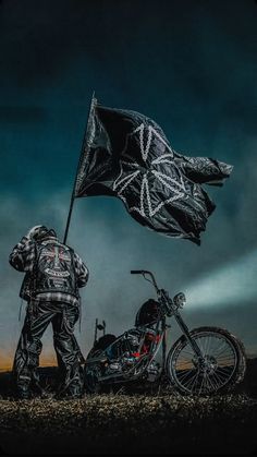 a man standing next to a motorcycle holding a flag