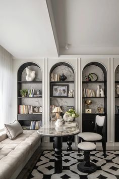 a living room filled with furniture and bookshelves next to a white couch on top of a black and white checkered floor