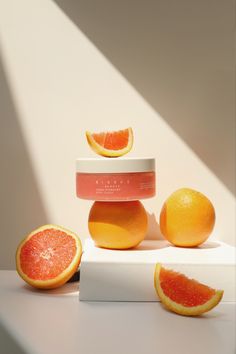 three oranges and one grapefruit sitting on top of a white box with the light coming through it