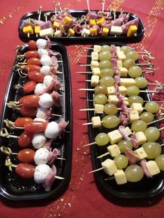 two trays filled with different types of food on skewers next to each other